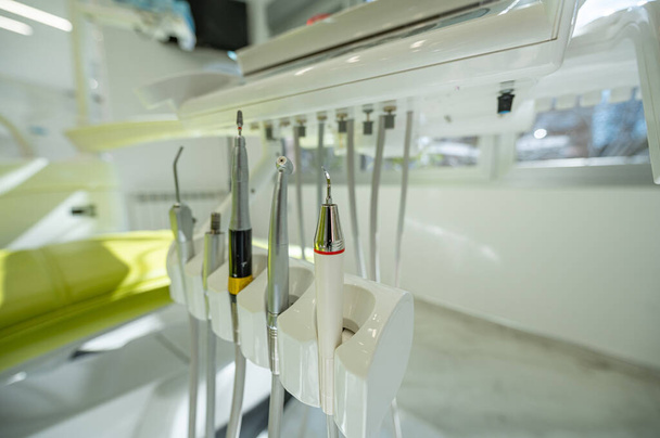 Detail van een tandheelkundig gereedschap bevestigd aan een tandartsstoel in een tandheelkundige kliniek. Tandheelkundige hygiëne en gezondheid conceptueel beeld. - Foto, afbeelding
