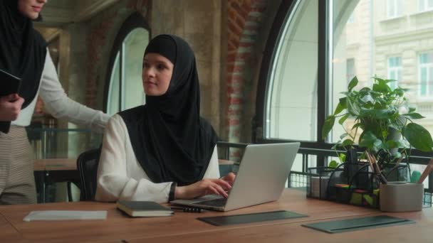Arabische zakenvrouw leider komen om werknemer te helpen laptop werk vrouwelijke mentor doceren student ondersteuning stagiair. Twee moslim islamitische zakenvrouwen in hijab meisjes werken samen bij kantoor bedrijf - Video