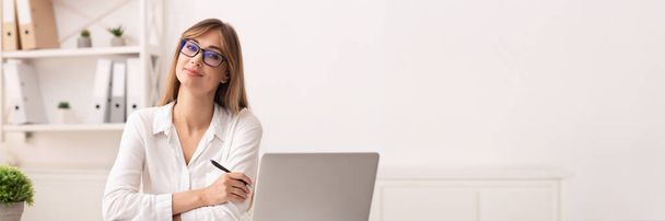 Предпринимательство. Уверенная деловая женщина улыбается перед камерой, сидя за ноутбуком в современном офисе, панорама с копировальным пространством - Фото, изображение