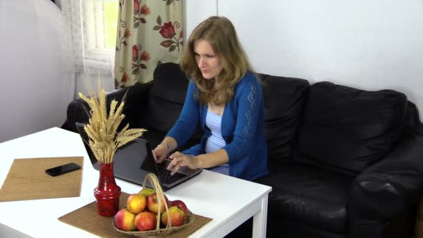 Вагітна жінка працює комп'ютером вдома, їсть червоне стигле яблуко
 - Кадри, відео