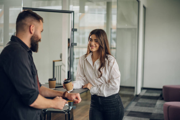 Two businesspeople chatting in an office. Excited caucasian female sharing ideas or startup business plan with male coworker. Work break concept. - Фото, изображение