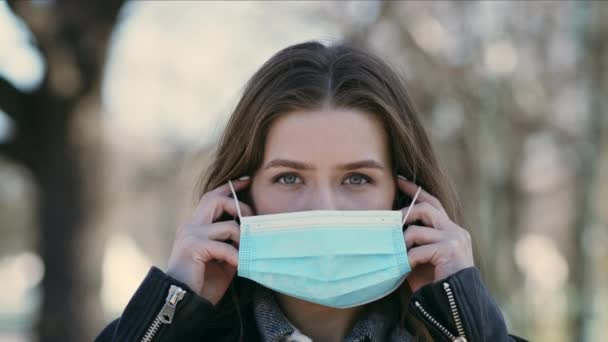 Jovem mulher colocando máscara médica para proteção contra coronavírus ao ar livre
 - Filmagem, Vídeo