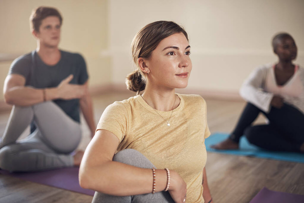 Jóga osztály, nő és csoport a szőnyegen csavart nyújtással, jólléttel vagy meditációval a wellness központban. Barátok, sokszínűség és fitness pilates a zen, holisztikus edzés és az egyensúly az emberek együtt. - Fotó, kép