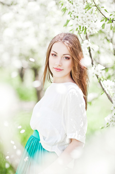 portrait of young lovely woman in spring flowers - Fotó, kép