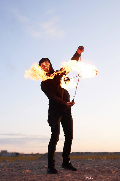 Ateş gösterisi sırasında gün batımında ateş yakan tanınmayan bir adamın dikey portresi. - Fotoğraf, Görsel