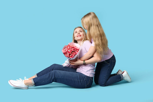 Roztomilé holčička dává kytice její maminka pro Den matek na modrém pozadí - Fotografie, Obrázek