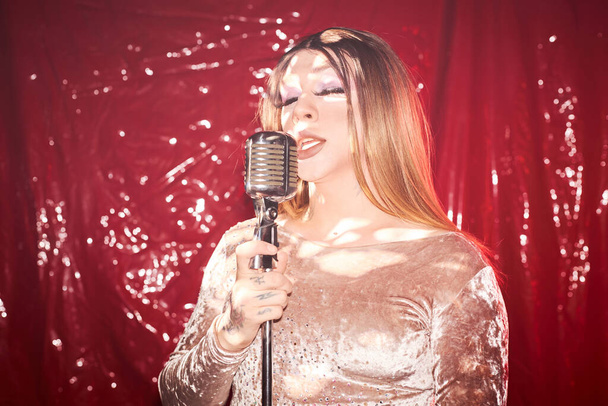 Sahne ışıkları altında şarkı söyleyen sarışın travesti portresi. - Fotoğraf, Görsel