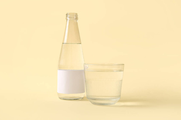 Bottiglia di acqua pulita e vetro su sfondo beige - Foto, immagini