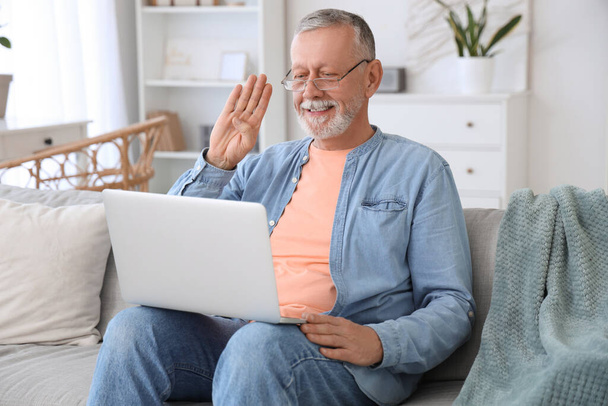 Зрелый глухонемой человек видео чата на языке жестов на диване дома - Фото, изображение
