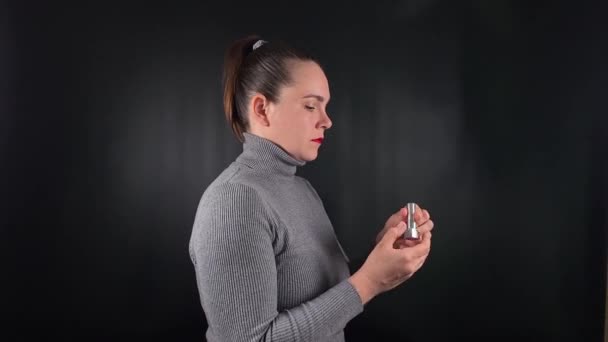 A young woman performs daily self-care routine, focusing on beauty and hygiene. Set against a sleek black background, her actions highlight the importance of maintaining personal wellness and grooming - Πλάνα, βίντεο
