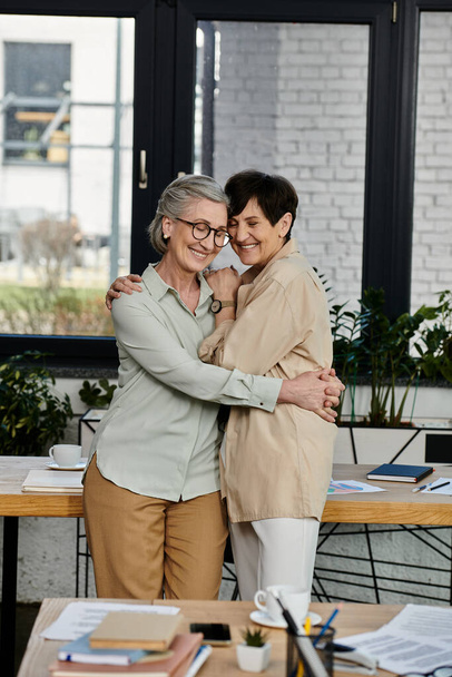 Δύο γυναίκες στο γραφείο, μοιράζονται μια ζεστή αγκαλιά. - Φωτογραφία, εικόνα