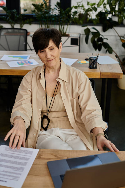 Une femme assise à une table, entourée de papiers, profondément réfléchie. - Photo, image
