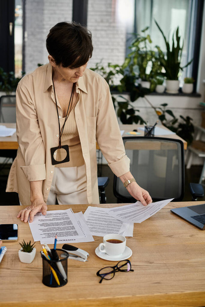Een vrouw staat aan een bureau omringd door papieren.. - Foto, afbeelding