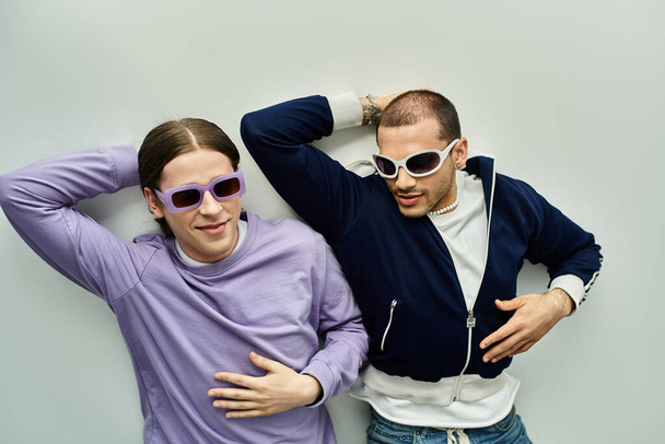 Двое молодых людей ставят перед камерой позу, излучая стиль и уверенность. - Фото, изображение