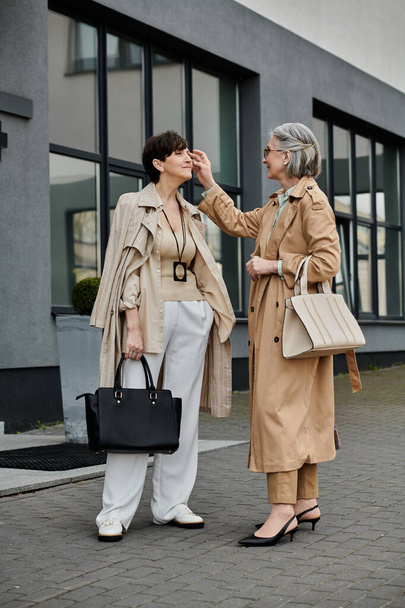 Dos mujeres, una pareja lesbiana madura y hermosa, de pie juntas frente a un edificio. - Foto, Imagen