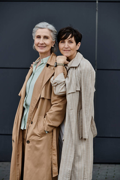 een volwassen mooi lesbisch paar staan samen in de voorkant van een gebouw. - Foto, afbeelding