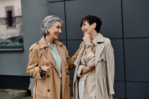 Две элегантные женщины стоят рядом с городским зданием. - Фото, изображение