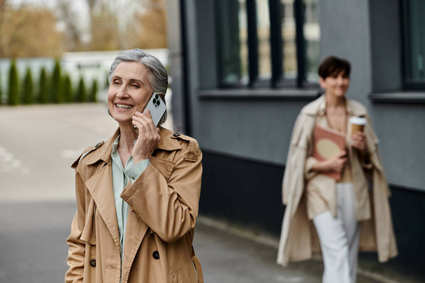Женщина болтает по телефону, прогуливаясь по улице со своим партнером. - Фото, изображение