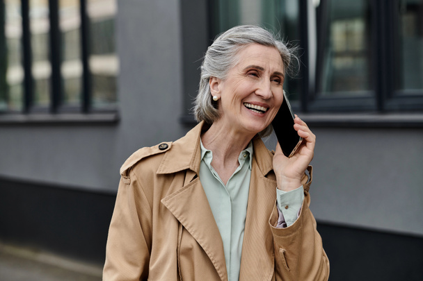 Une élégante femme âgée bavardant sur son téléphone portable. - Photo, image