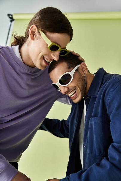 Ein trendiges homosexuelles Paar genießt die gemeinsame Zeit und posiert mit Sonnenbrille. - Foto, Bild
