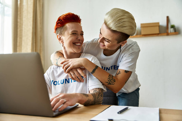 Ein Mann und eine Frau umarmen sich, während sie auf einen Laptop schauen, und engagieren sich mit Empathie und Geschlossenheit in ehrenamtlicher Arbeit. - Foto, Bild
