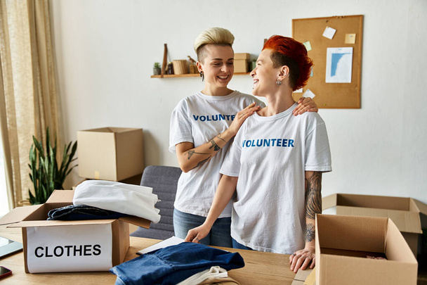Two women in volunteer t-shirts working together in a room. - Fotó, kép