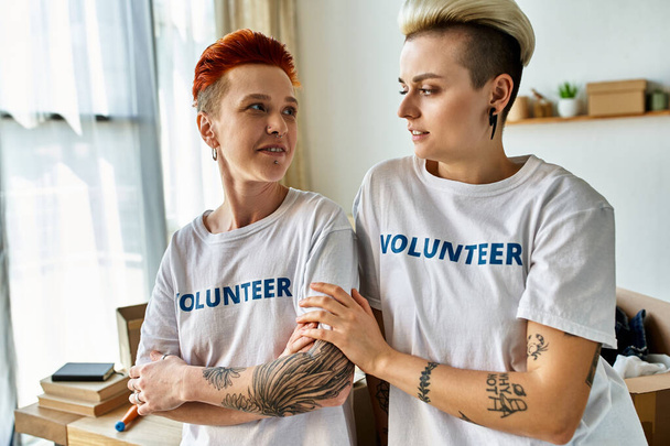 Młoda lesbijska para, ubrana w ochotnicze koszulki, stoi obok siebie, aktywnie angażując się w działalność charytatywną. - Zdjęcie, obraz