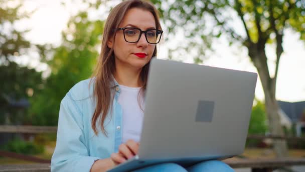 Žena sedí v parku, pracuje na laptopu a pije kávu.. - Záběry, video