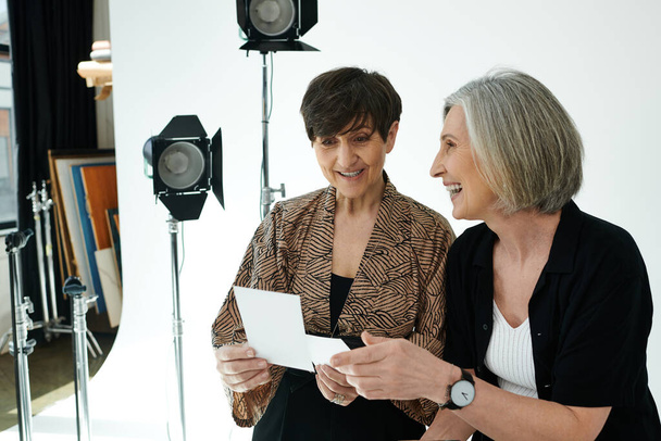 Un fotografo di mezza età cattura la bellezza di un modello in un ambiente di studio, guardando la foto stampata - Foto, immagini