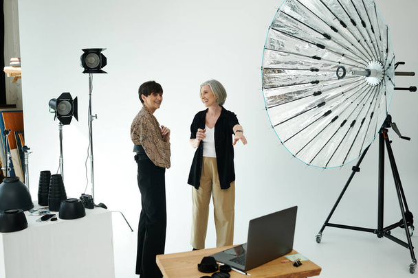 Un fotógrafo charlando con una modelo en un estudio fotográfico, pareja lesbiana - Foto, imagen
