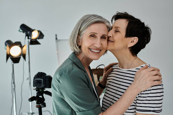 A middle-aged lesbian couple share a tender kiss in a photo studio - Photo, Image