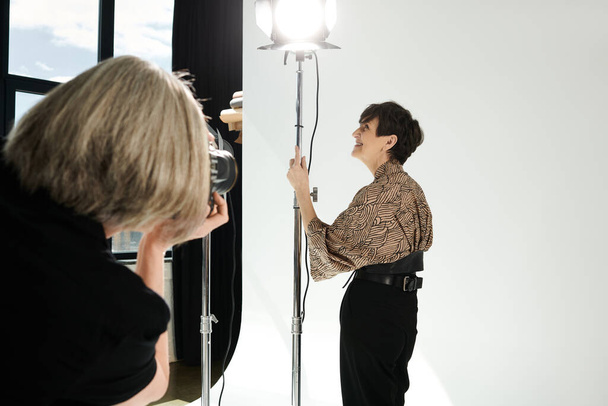 Kobieta w średnim wieku uchwyca się w lustrze, czułej chwili wyrażania siebie i miłości do siebie w studiu fotograficznym. - Zdjęcie, obraz