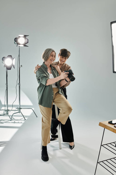 Ένα μεσήλικο λεσβιακό ζευγάρι σε ένα στούντιο, να τσεκάρει φωτογραφίες στην κάμερα - Φωτογραφία, εικόνα
