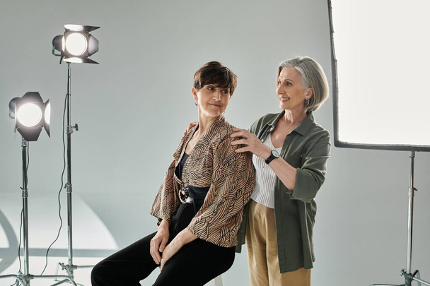 Lesbijki w studio, jedna kobieta pokazuje pozę modelce - Zdjęcie, obraz
