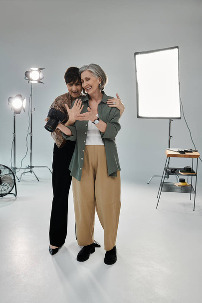Middle aged lesbian couple in a studio, one with camera showing photos - Photo, Image