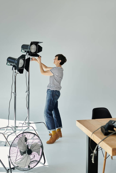 Una donna cattura creativamente il mondo da una prospettiva unica, in piedi su una sedia e regolando softbox - Foto, immagini
