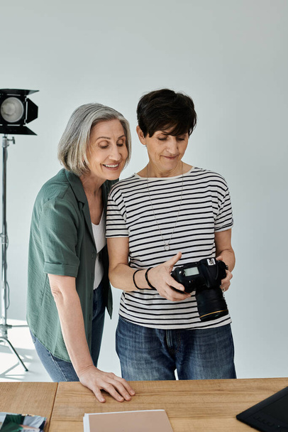 Dos mujeres de mediana edad mirando a la cámara profesional en un moderno entorno de estudio de fotos. - Foto, Imagen