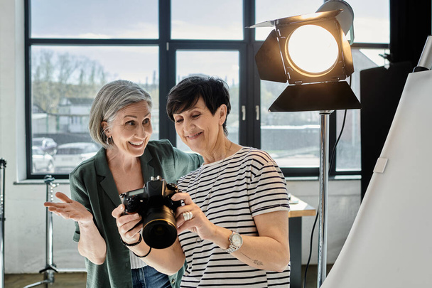 pareja de lesbianas de mediana edad con confianza se encuentra lado a lado en un moderno estudio de fotos. - Foto, imagen