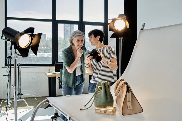 A middle-aged woman taking a picture of bags in a professional photo studio setup. - Photo, Image