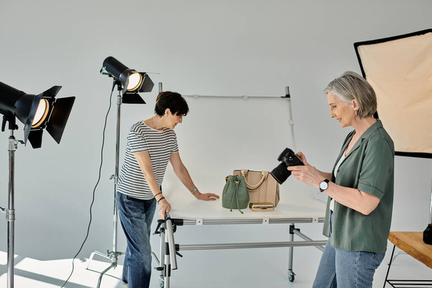 Para w średnim wieku, trzymająca aparat fotograficzny, współpracująca w nowoczesnym studiu fotograficznym. - Zdjęcie, obraz