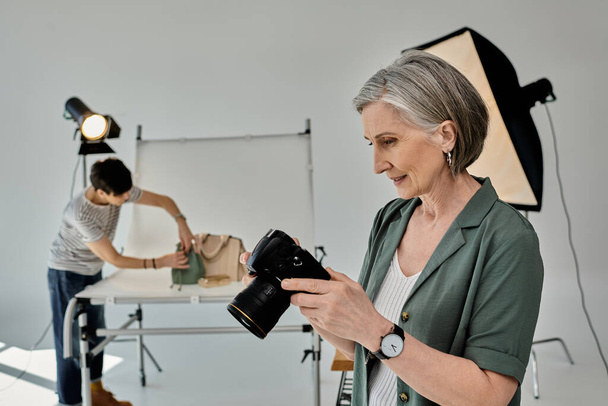 A middle-aged woman holds a camera in a modern photo studio setting. - Photo, Image