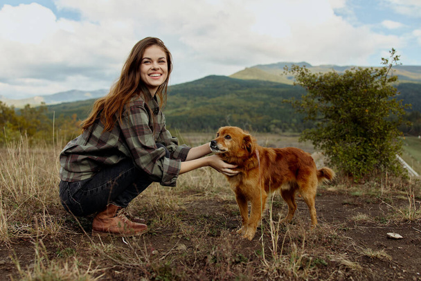 Woman bonding with her loyal companion in a serene field amidst majestic mountains in a peaceful travel moment - Foto, Imagem