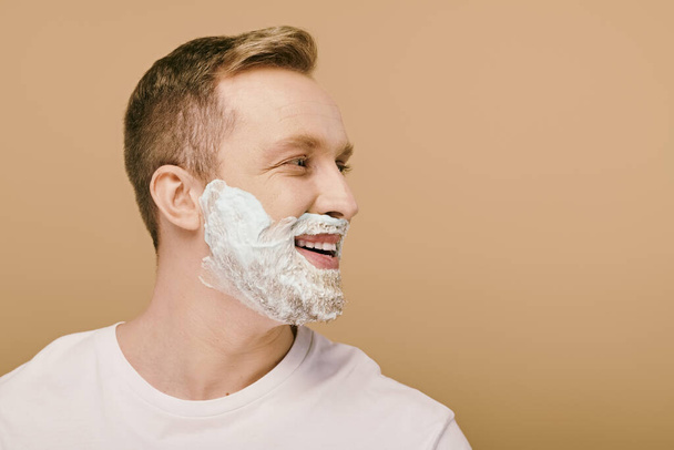 Ένας άντρας με απλή ενδυμασία ετοιμάζεται να ξυρίσει το πρόσωπό του.. - Φωτογραφία, εικόνα