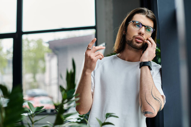 Белый мужчина в длинных волосах и очках разговаривает по мобильному телефону. - Фото, изображение