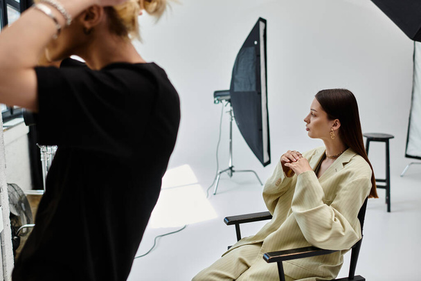 Una mujer se sienta cerca de su maquilladora en un estudio fotográfico. - Foto, imagen