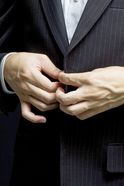 Un homme d'affaires range le bouton de son costume
 - Photo, image