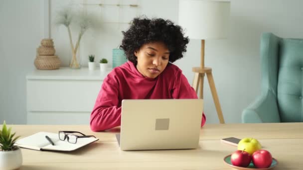 Африканская американка использует ноутбук в домашнем офисе, смотрит на экран, печатает чаты, пишет электронную почту. Молодая женщина проводит виртуальную встречу онлайн чат видео-конференции. Обучение работе на дому - Кадры, видео