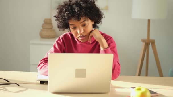 Chica afroamericana utilizando ordenador portátil que tiene chat de vídeo en casa. Mujer joven que tiene una reunión virtual de chat en línea de videoconferencia. Aprendizaje desde casa, profesor remoto - Metraje, vídeo