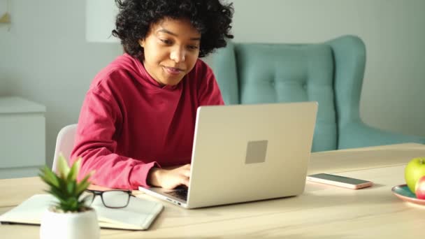 Африканська дівчина-американка використовує ноутбук у себе вдома, спостерігаючи за розмовною розмовною розмовою на екрані з письмовою поштою. Молода жінка проводить віртуальну конференцію онлайн-дзвінків. Навчайся вдома - Кадри, відео