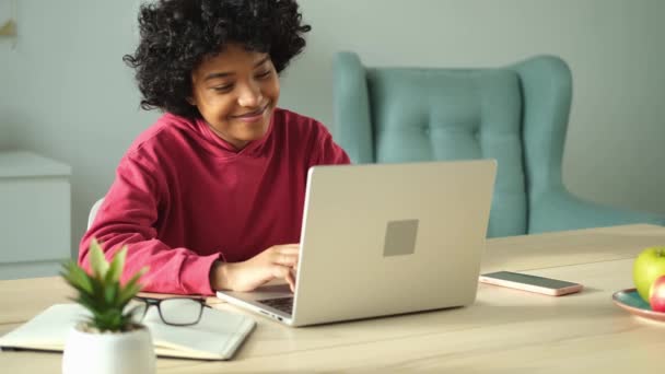 Африканская американка использует ноутбук в домашнем офисе, смотрит на экран, печатает чаты, пишет электронную почту. Молодая женщина проводит виртуальную встречу онлайн чат видео-конференции. Обучение работе на дому - Кадры, видео